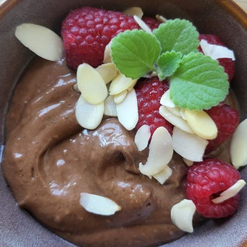 mus kakaowy bez cukru i nabiału w miseczce składniki do musu kakaowego z awokado kremowy mus czekoladowy z awokado mus kakaowy posypany owocami i orzechami deser przeciwzapalny bez cukru mieszanie składników na mus kakaowy szybki mus kakaowy dla jelit